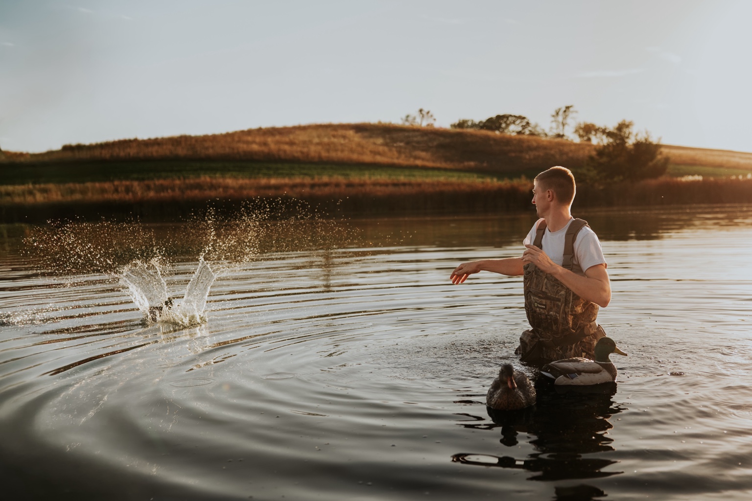 A senior skipping a stone across a quiet Nebraska pond at golden hour