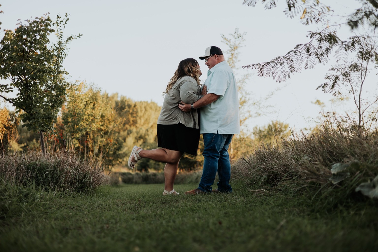 A couple embracing beside trees and grass