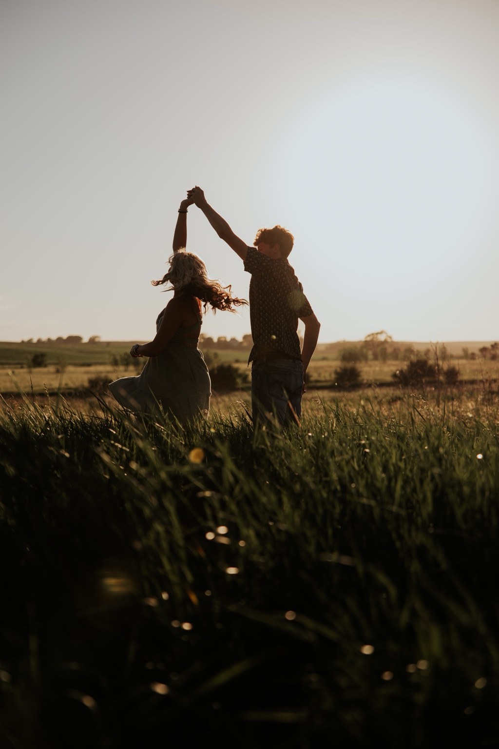 A couple dancing in a field at sunset