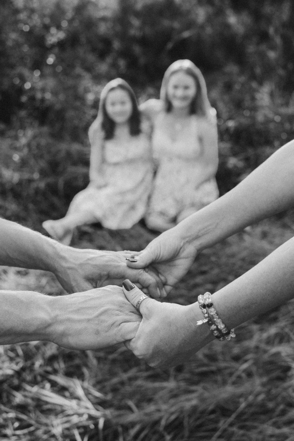Parents holding hands with their daughters in the background