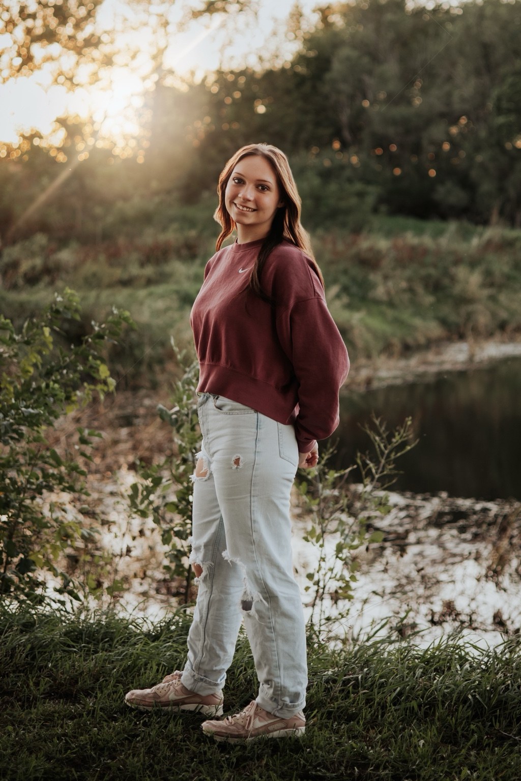 Senior portrait beside a pond in warm evening light