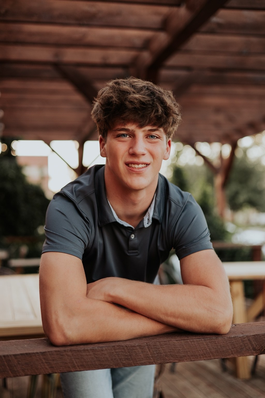Senior smiling beneath a rustic wooden shelter