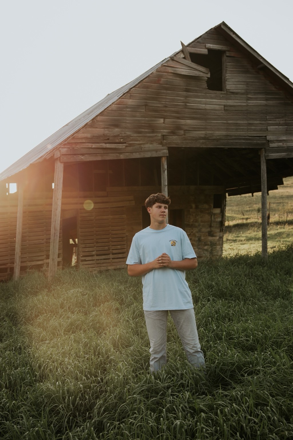 Senior standing in front of a weathered barn