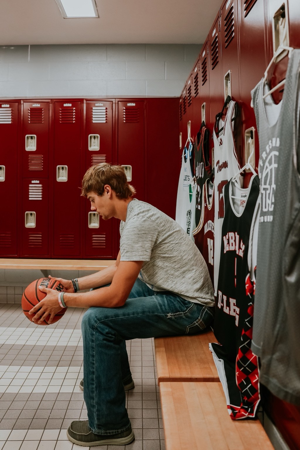 Senior holding a basketball in a locker room