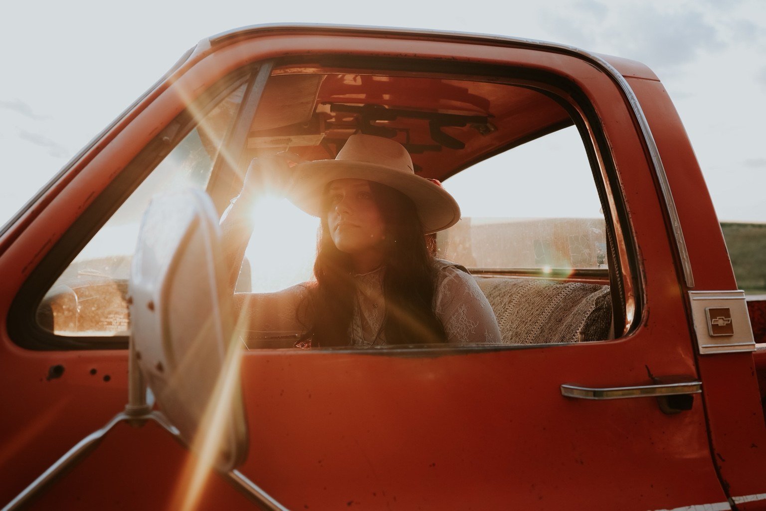 Senior in a vintage red truck at sunset