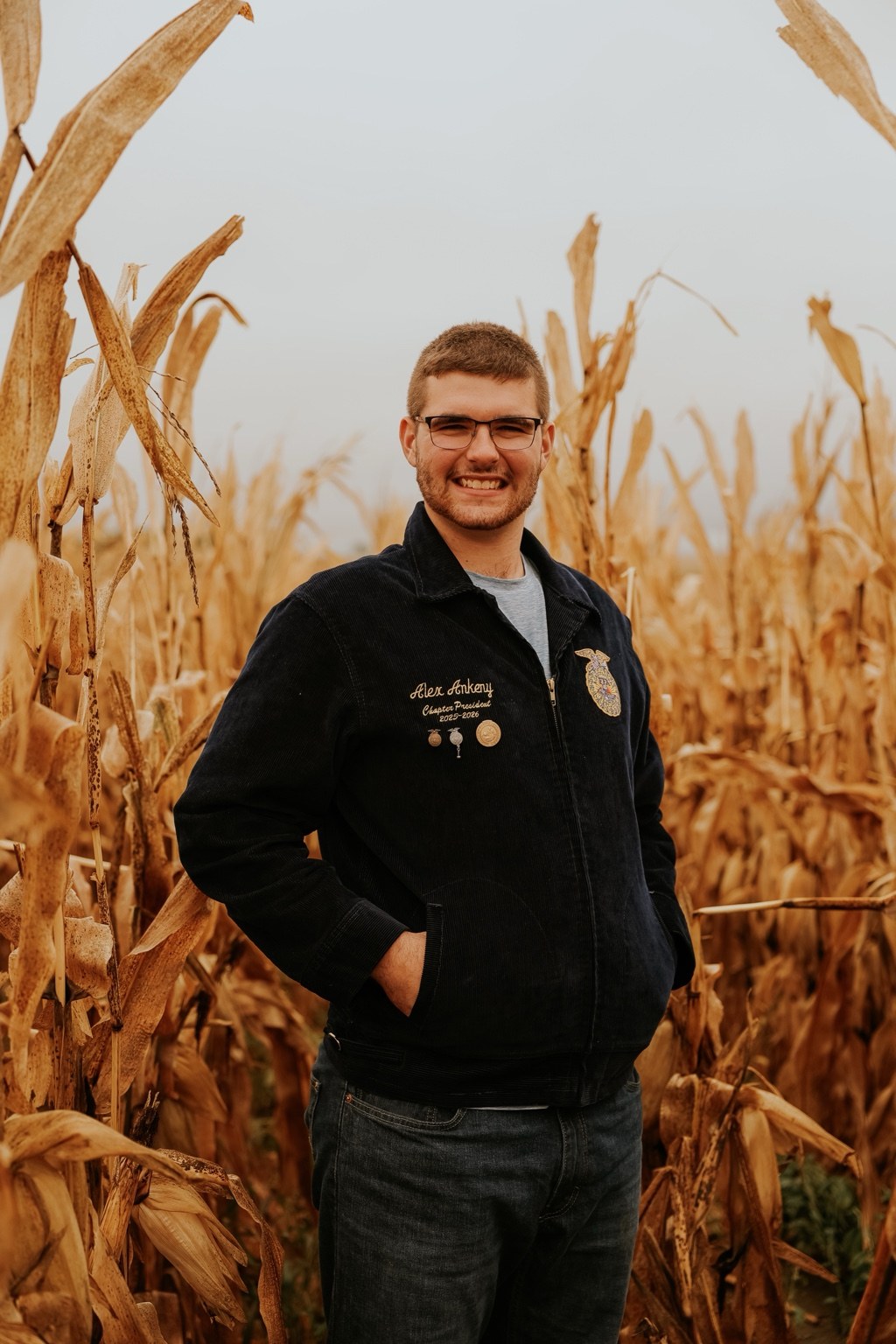 Senior wearing an FFA jacket in a cornfield