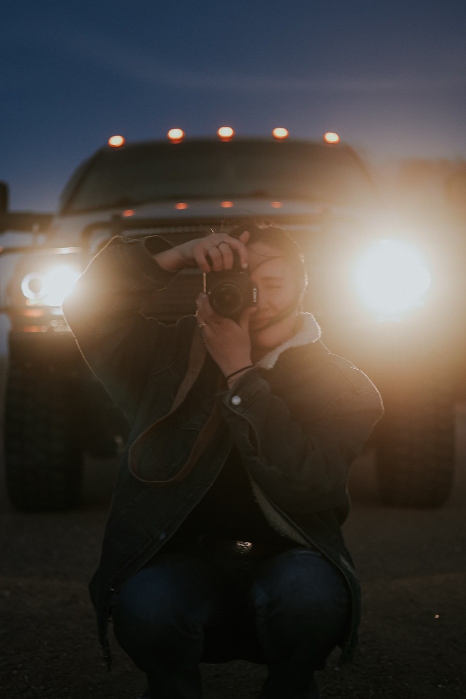 Taylor with her camera in front of a truck at dusk
