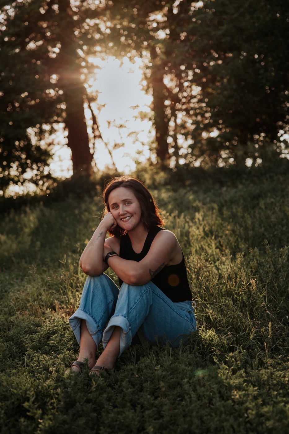 Taylor smiling in the grass beneath warm evening sunlight