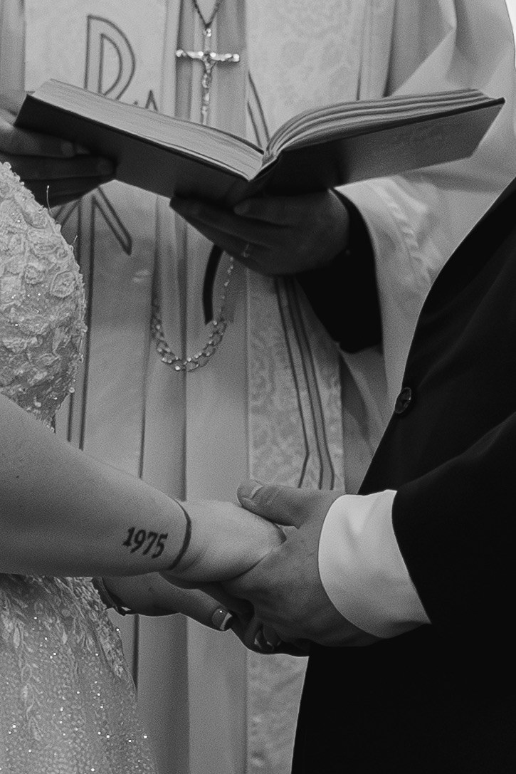 Black and white detail of the couple holding hands during the ceremony
