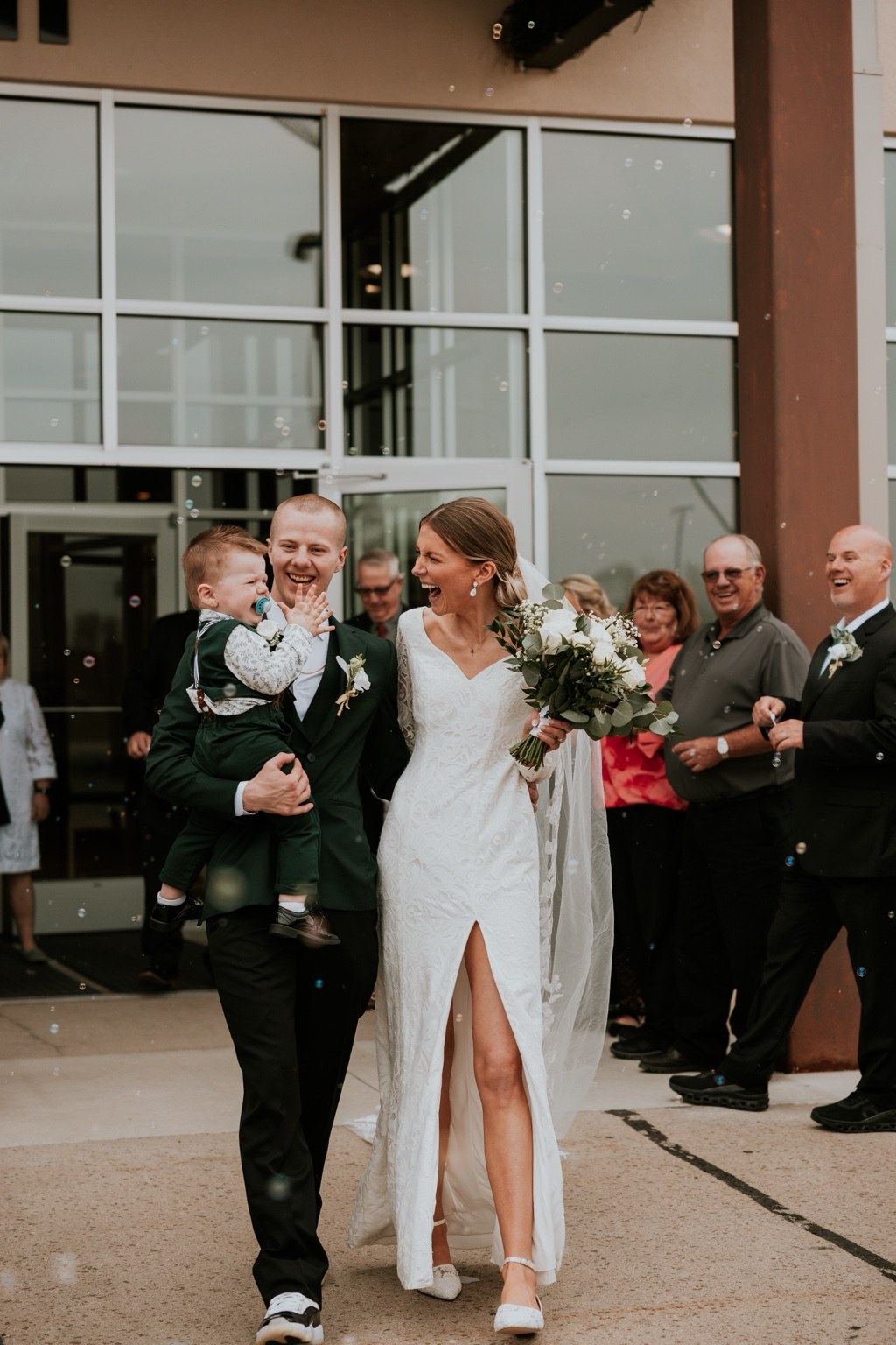 Newlyweds celebrating outside with a child and their guests