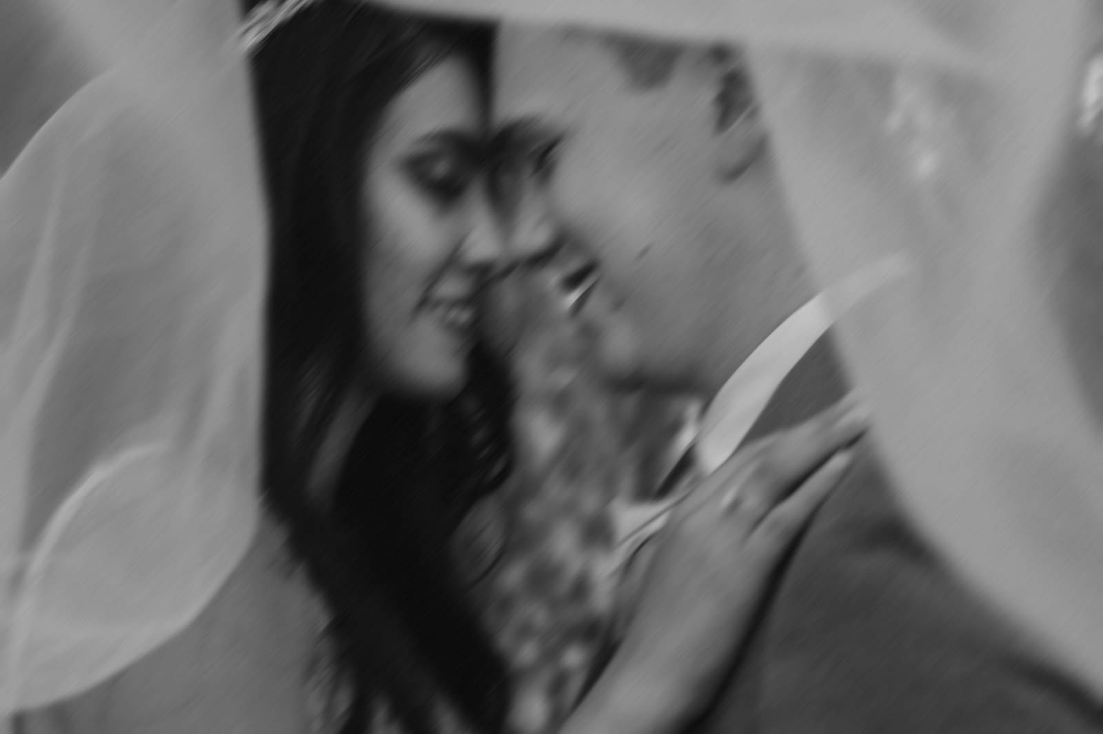 Black and white portrait of a couple beneath a wedding veil