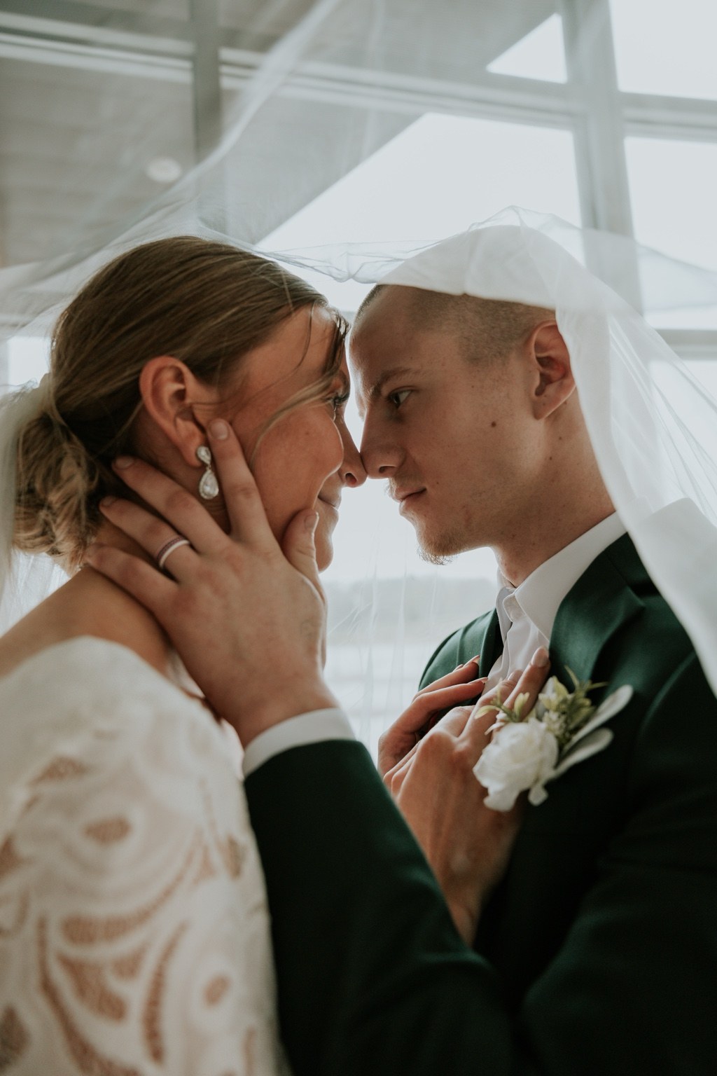 A close-up of newlyweds beneath a sheer veil