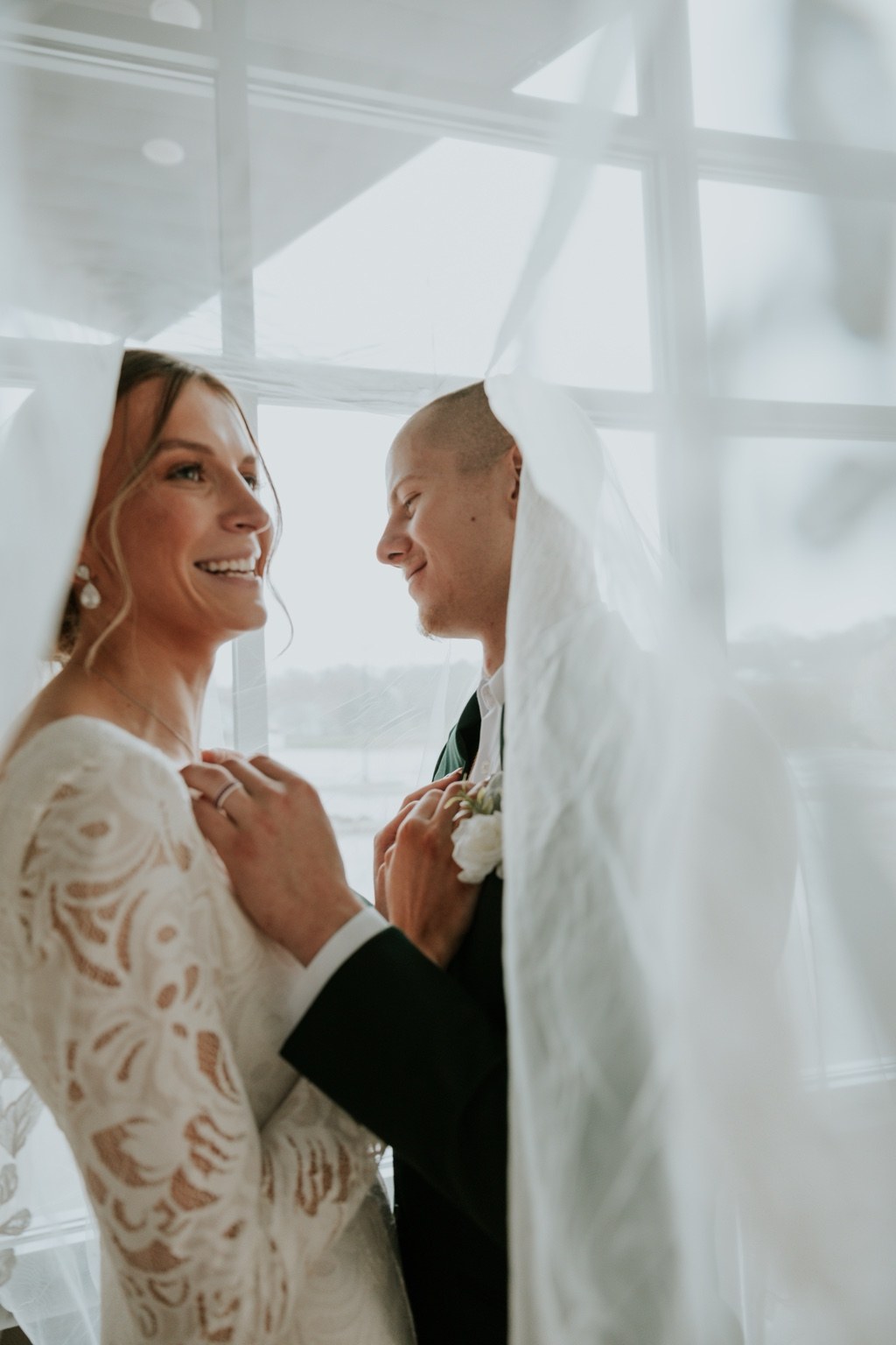 A bride smiling beside her groom beneath her veil