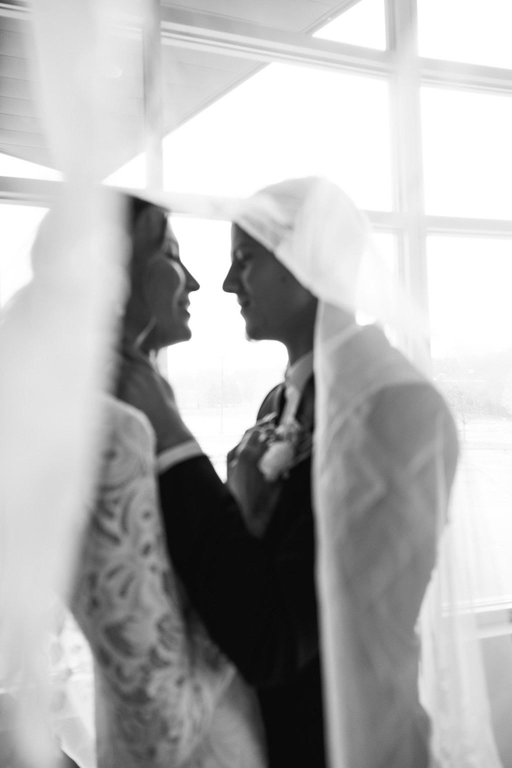 Black and white portrait of a couple facing each other beneath a veil