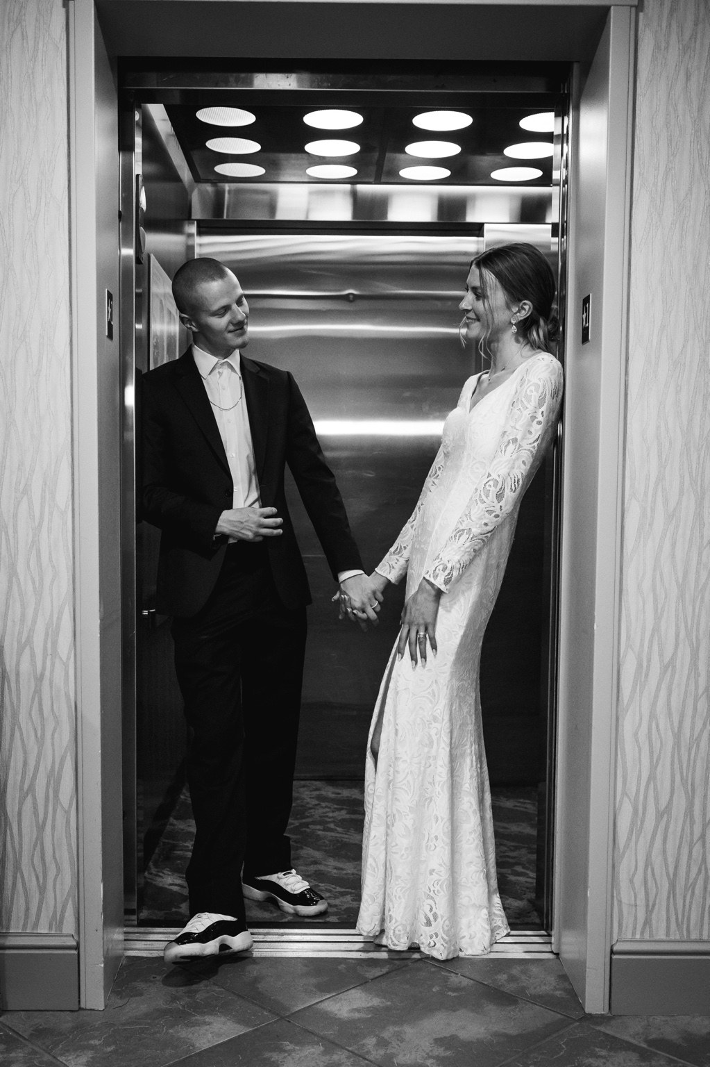 Newlyweds holding hands in an elevator