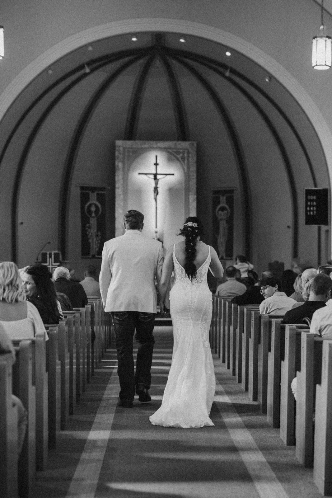 Black and white photograph of a couple walking down the church aisle